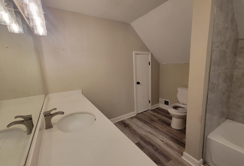 Bathroom with toilet, vanity, wood finished floors, and lofted ceiling