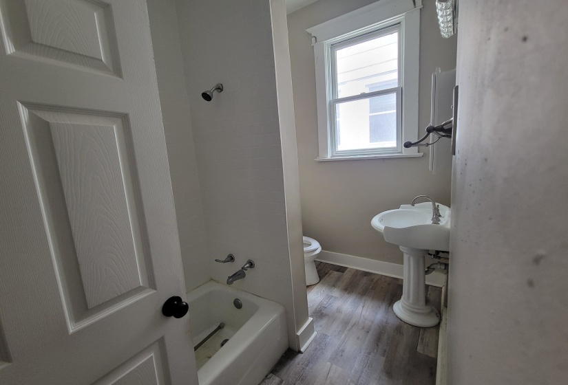 Bathroom featuring toilet, wood finished floors, bathing tub / shower combination, and baseboards