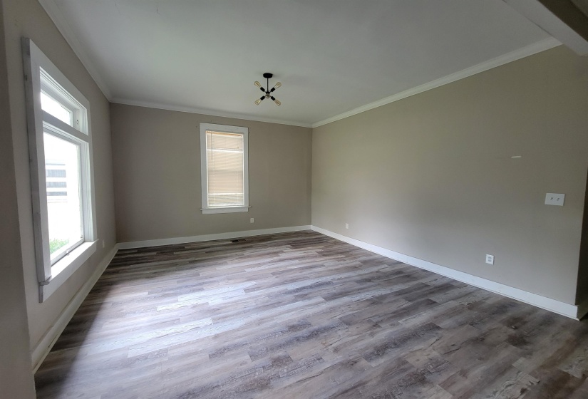 Unfurnished room with plenty of natural light, wood finished floors, baseboards, and ornamental molding