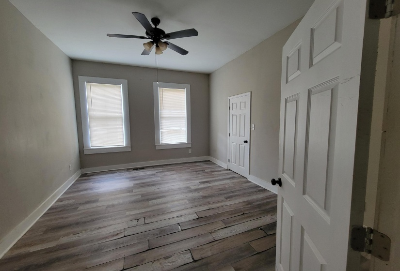 Unfurnished bedroom featuring wood finished floors, baseboards, and a ceiling fan