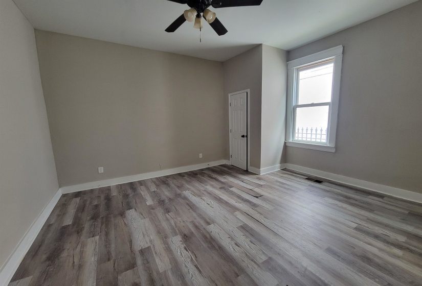 Empty room featuring wood finished floors, a ceiling fan, and baseboards