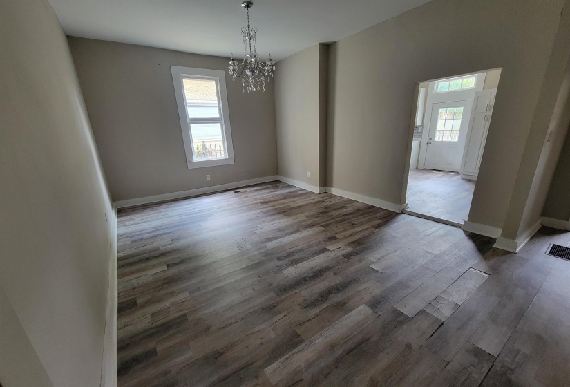 Unfurnished dining area with a chandelier, wood finished floors, and baseboards