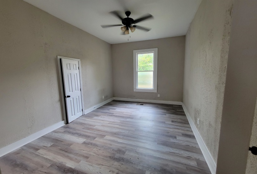 Empty room featuring a textured wall, wood finished floors, ceiling fan, and baseboards