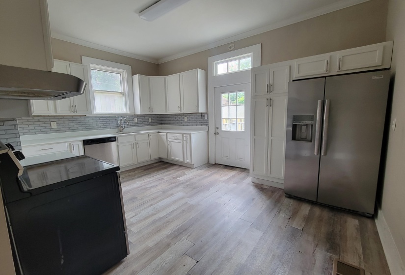 Kitchen with stainless steel appliances, crown molding, a sink, white cabinetry, and decorative backsplash