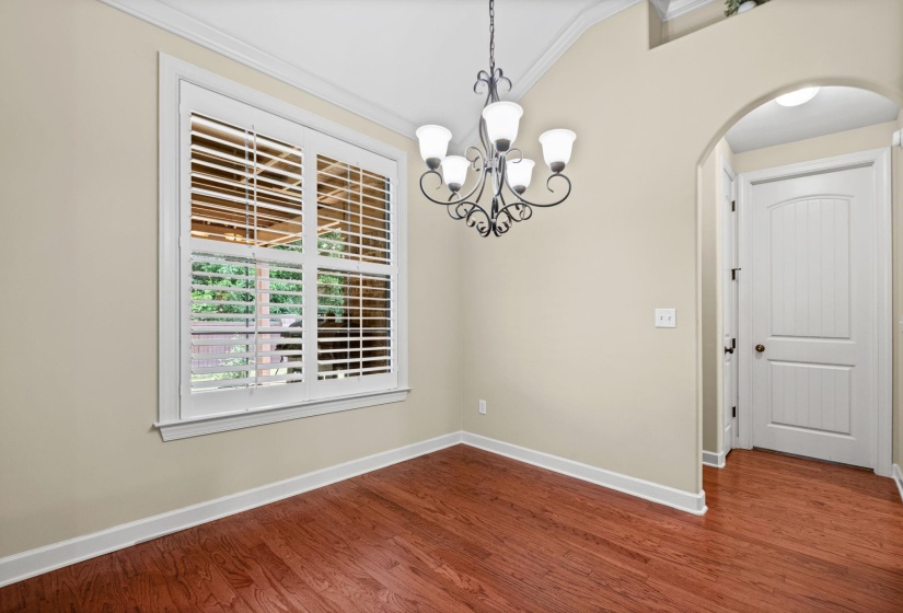 Interior space featuring wood-finish flooring, a decorative chandelier, and a window with plantation shutters