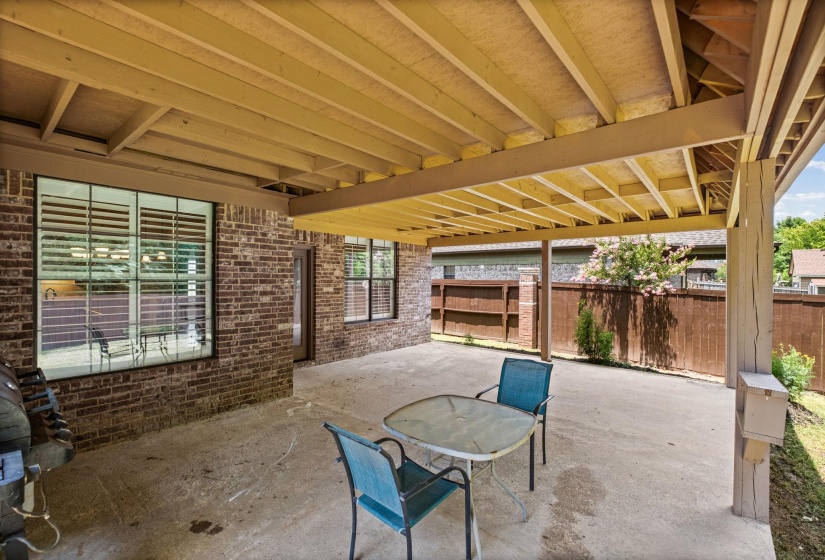 Expansive covered patio featuring a concrete surface, exposed wood ceiling, and brick exterior wall
