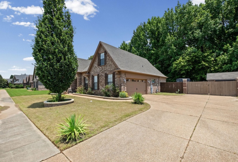 Brick exterior residence featuring a two-car garage, concrete driveway, and mature landscaping