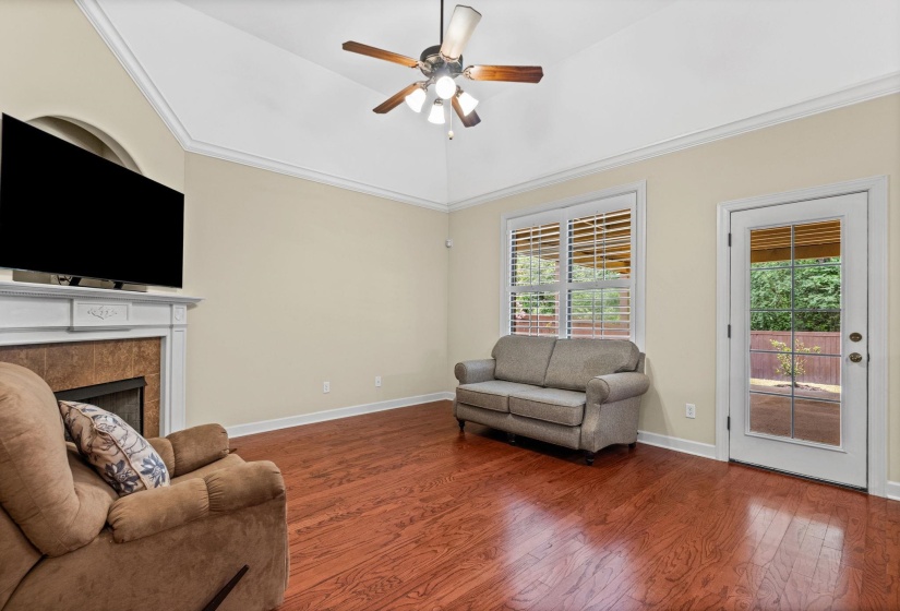 Living space featuring wood-finish flooring, a vaulted ceiling, and a fireplace with a tile surround and white mantel