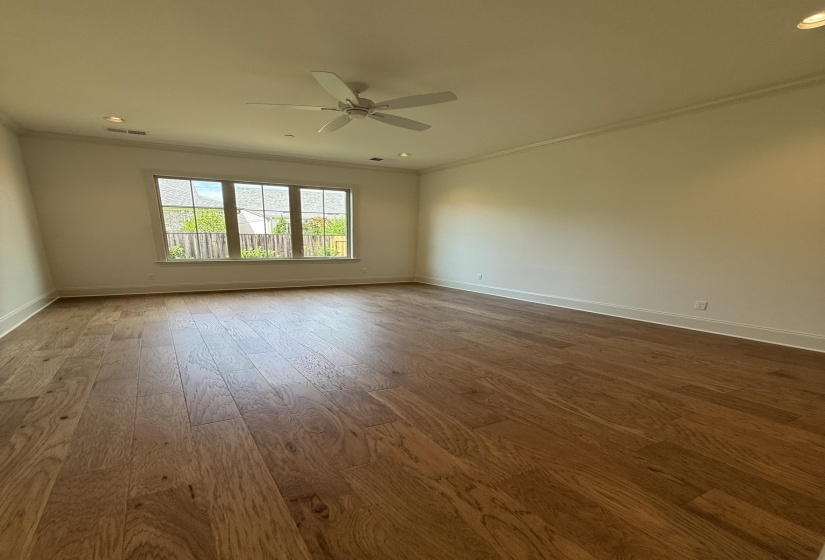 Spacious room featuring wood-finish flooring, a ceiling fan, recessed lighting, and crown molding