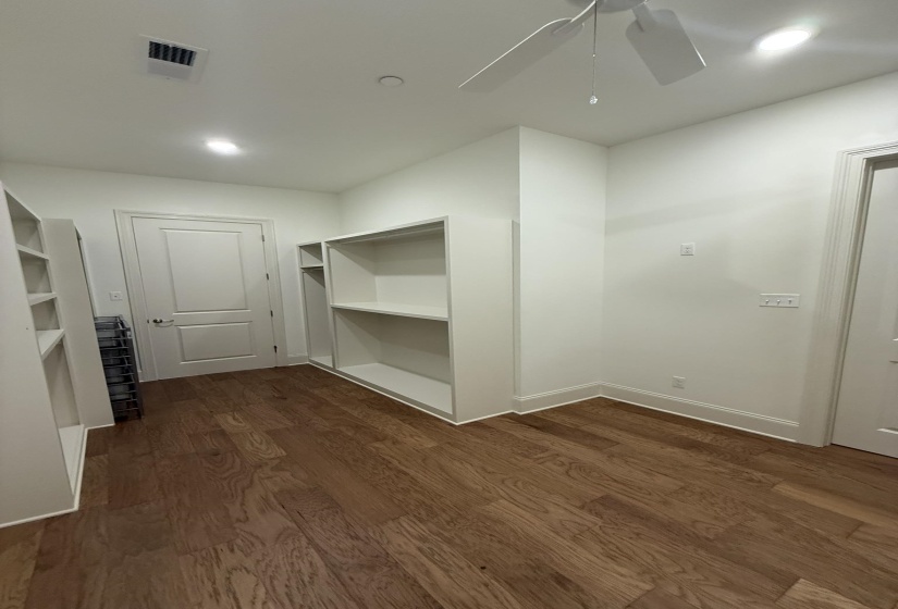 Room featuring built-in shelving, wood-finish flooring, a ceiling fan, and recessed lighting
