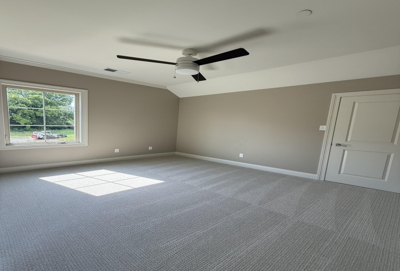 Spacious room featuring new carpeting, a modern ceiling fan with lighting, and a large window