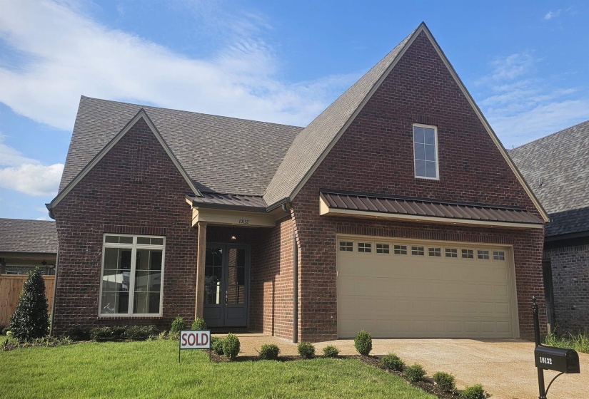 Brick exterior featuring a gabled roofline, a two-car garage with transom windows, a covered entryway, and a dark-paneled front door