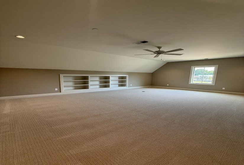 Spacious carpeted room featuring a ceiling fan, recessed lighting, and built-in shelving
