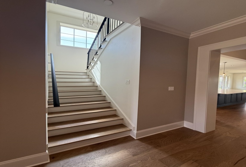 Staircase with wood-finish treads, white risers, and black metal railings