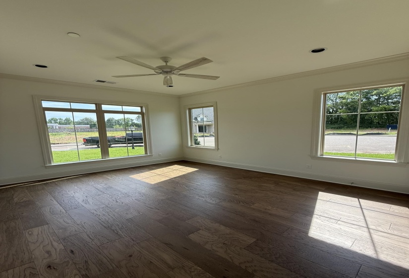 Spacious room featuring wood-finish flooring, white walls, and multiple windows