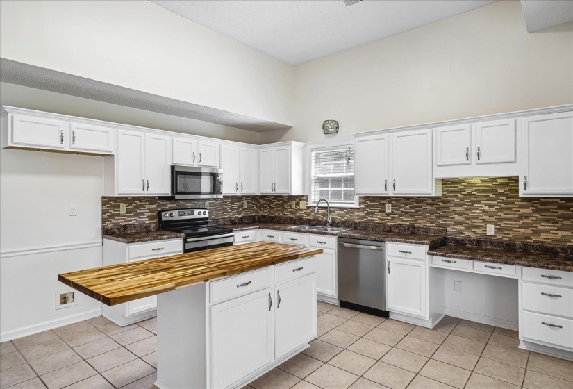 Kitchen with vaulted ceilings, white cabinetry, and a mosaic tile backsplash
