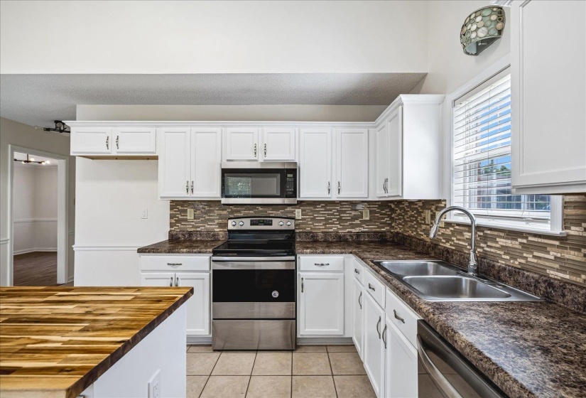 Kitchen featuring white cabinetry, a mosaic tile backsplash, and dark speckled countertops
