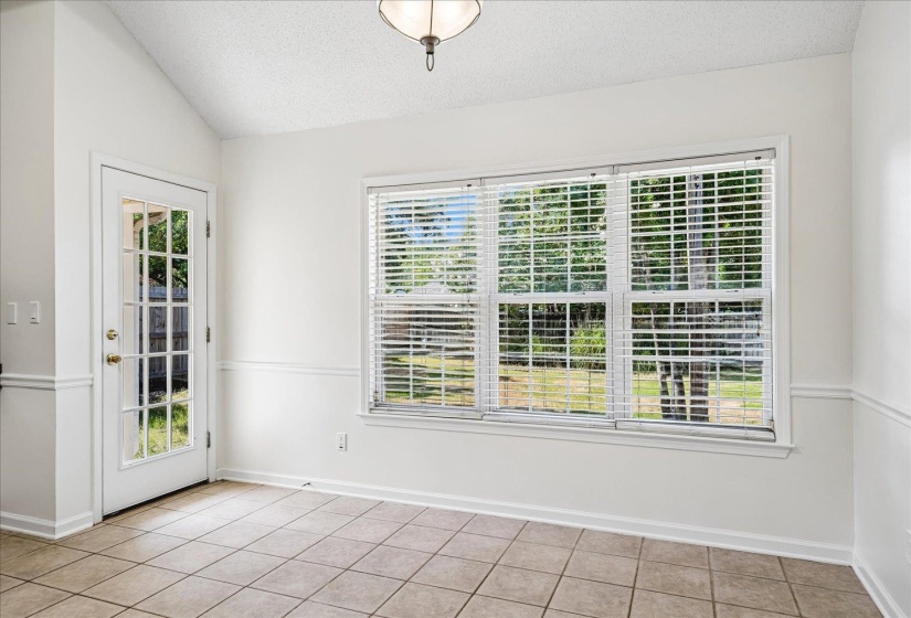 Room featuring tile flooring, wainscoting, a vaulted ceiling, and a glass-paneled exterior door