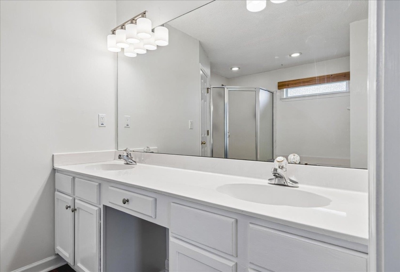 Double vanity with integrated sinks, white cabinetry, chrome fixtures, and an expansive mirror