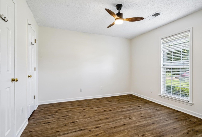 Spacious room featuring wood-finish flooring, white walls, and a ceiling fan with integrated lighting