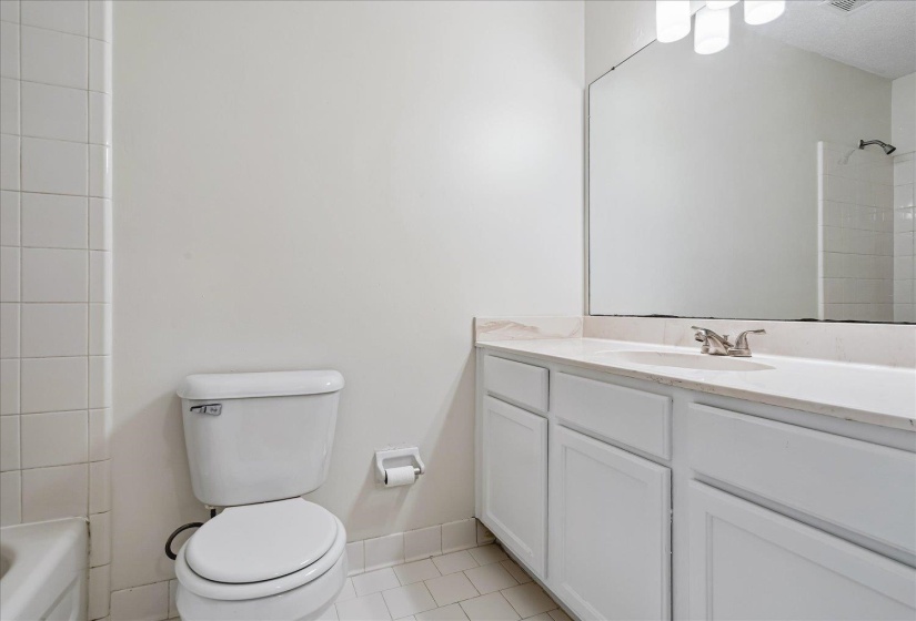 Bathroom featuring a single vanity with white cabinetry, light-toned countertop, and an integrated sink