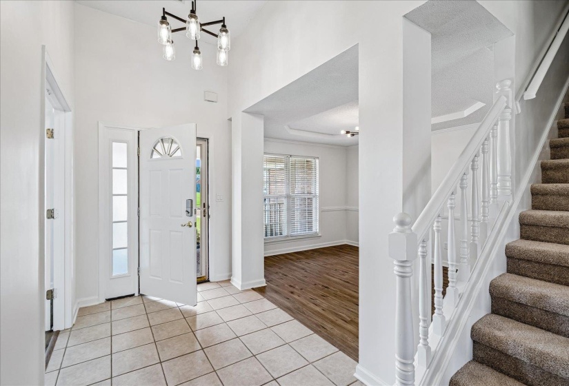 Foyer entry featuring ceramic tile flooring, a modern chandelier, and a white paneled front door with sidelights