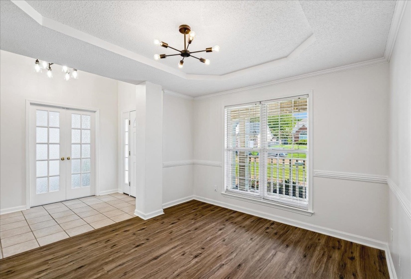 Spacious room featuring wood-finish flooring, a tray ceiling, and a modern sputnik chandelier