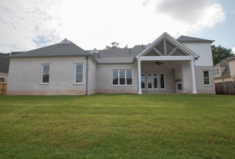 Rear view of property featuring ceiling fan and a lawn