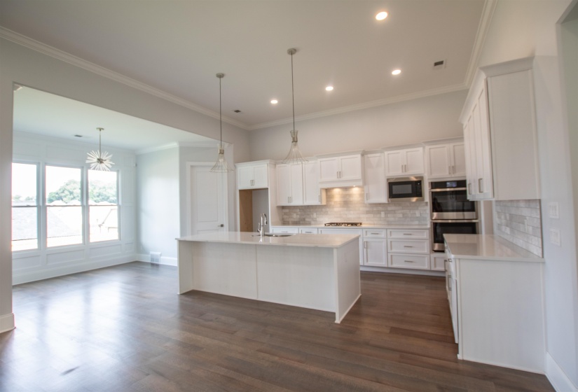Kitchen with stainless steel appliances, decorative backsplash, dark hardwood / wood-style floors, an island with sink, and white cabinetry