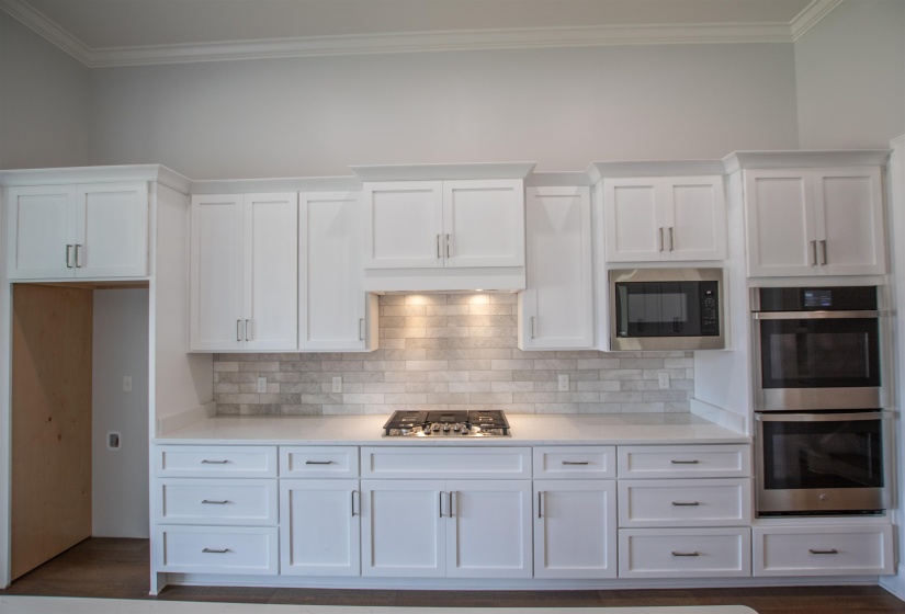 Kitchen with appliances with stainless steel finishes, white cabinets, dark hardwood / wood-style floors, and crown molding