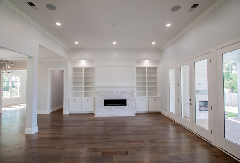 Unfurnished living room featuring plenty of natural light, a fireplace, dark wood-type flooring, and built in shelves