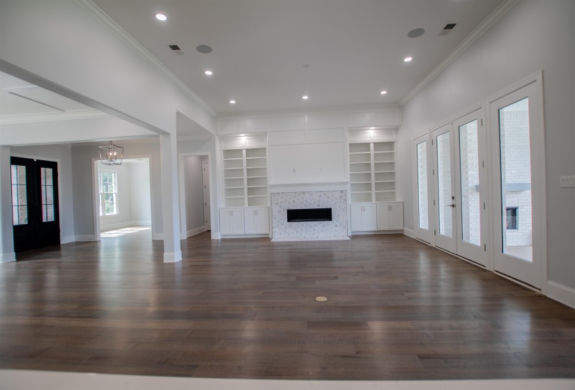 Unfurnished living room with a tile fireplace, built in shelves, dark hardwood / wood-style flooring, and french doors