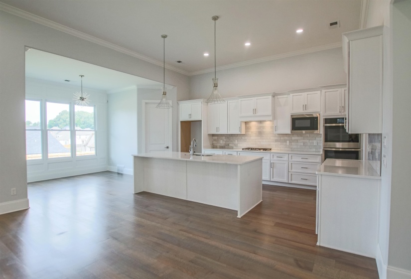 Kitchen featuring tasteful backsplash, white cabinets, a kitchen island with sink, dark hardwood / wood-style floors, and stainless steel appliances