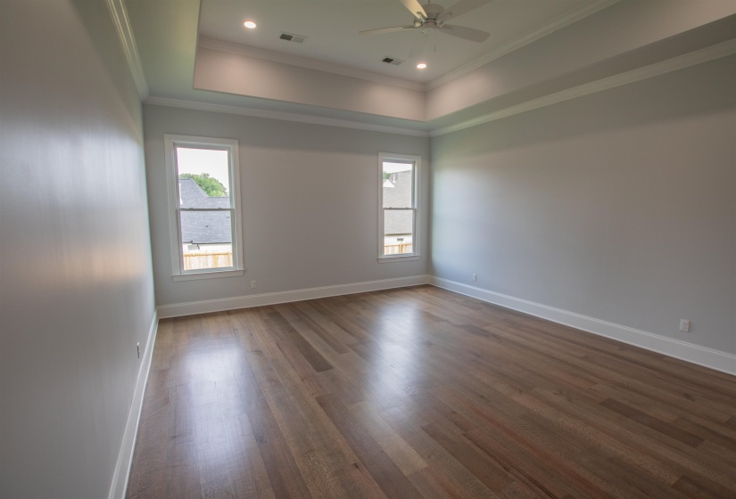 Spare room featuring ceiling fan, hardwood / wood-style flooring, crown molding, and a tray ceiling