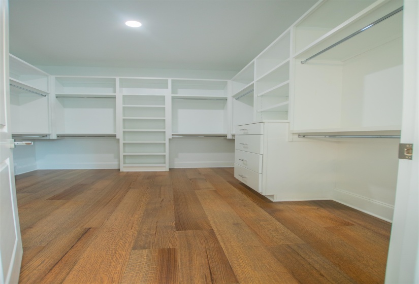 Walk in closet with hardwood / wood-style flooring