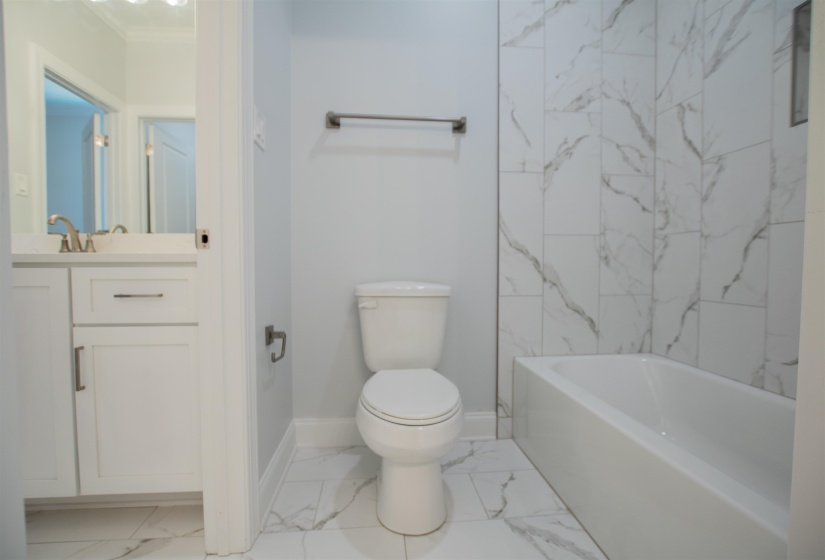 Full bathroom with crown molding, toilet, tile patterned floors, vanity, and tiled shower / bath combo