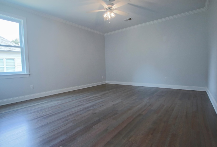 Empty room with ceiling fan, wood-type flooring, and ornamental molding