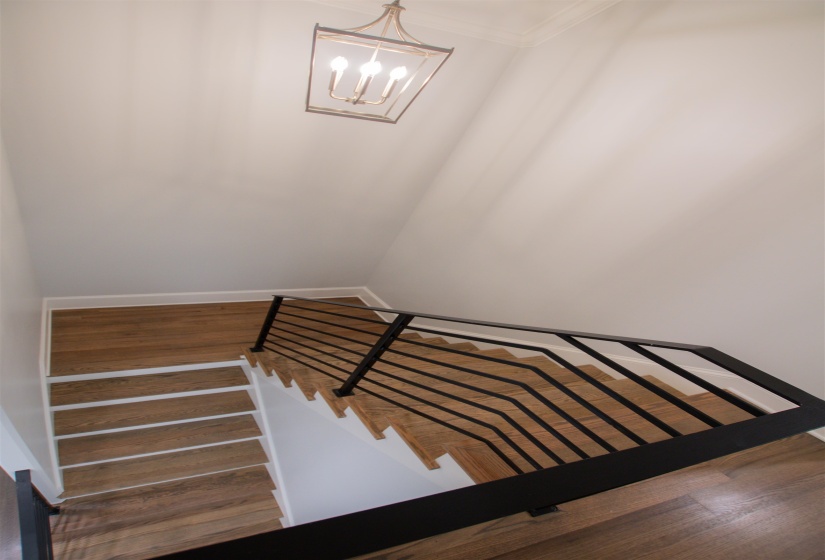Stairs featuring ornamental molding, an inviting chandelier, and hardwood / wood-style flooring
