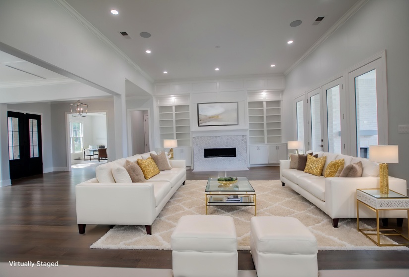 Living room featuring ornamental molding, wood finished floors, built in shelves, a fireplace, and baseboards