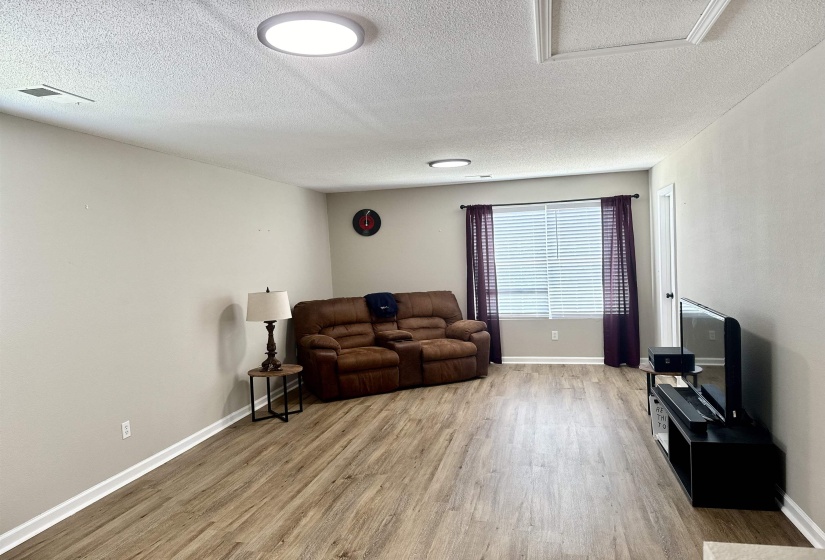 Living room featuring  wood-type flooring, lots of natural light. Adjoining bedroom 2 and hallway to rd and Primary bedroom