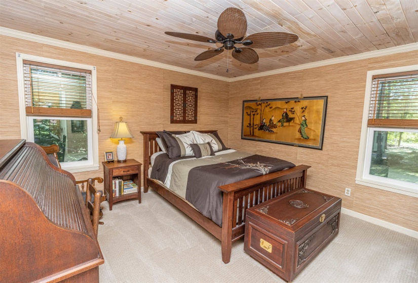 Carpeted bedroom featuring ornamental molding, ceiling fan, wood walls, and wood ceiling