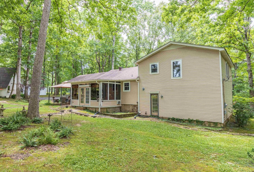 Rear view of house with a sunroom and a lawn