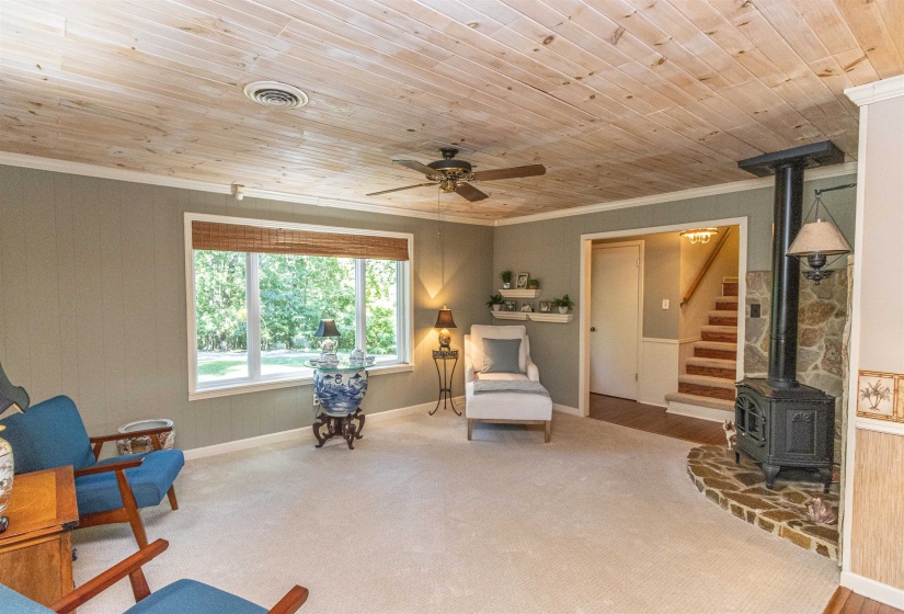 Living area with a wood stove, ornamental molding, and wooden ceiling