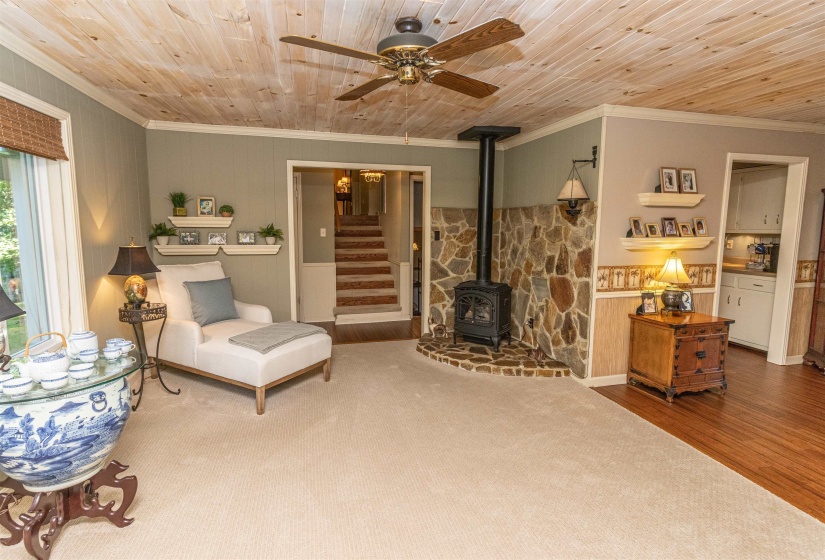 Living room featuring a wood stove, wood ceiling, ceiling fan, hardwood / wood-style flooring, and ornamental molding