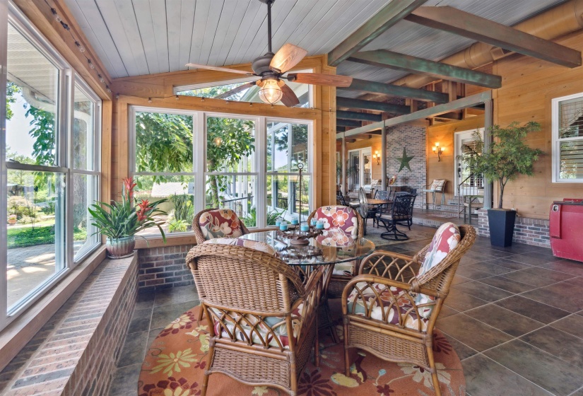 Sunroom with lofted ceiling with beams, wooden ceiling, ceiling fan, and a wealth of natural light