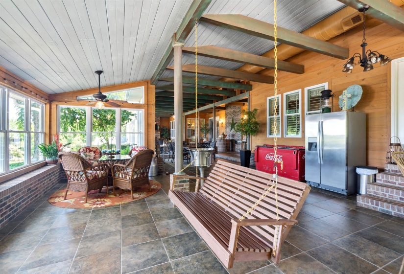 Sunroom / solarium with vaulted ceiling with beams, wooden ceiling, and ceiling fan with notable chandelier