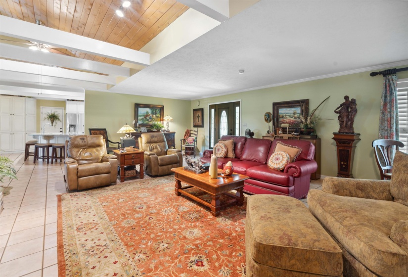 Living room featuring beamed ceiling, wood ceiling, tile patterned flooring, and ceiling fan