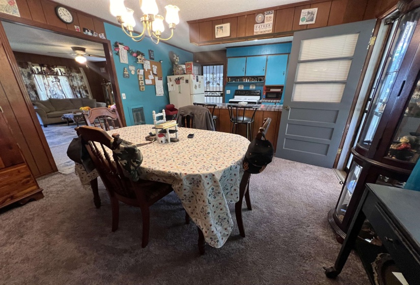 Dining space with carpet flooring and ceiling fan with notable chandelier