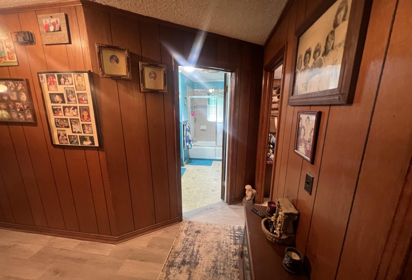 Corridor featuring wood walls, light colored carpet, and a textured ceiling