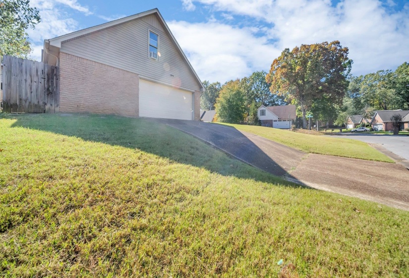 View of side of home featuring a garage and a lawn